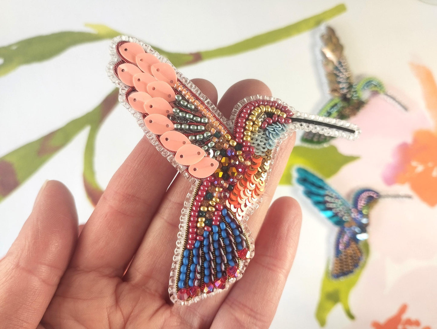 a person holding a colorful bird brooch in their hand