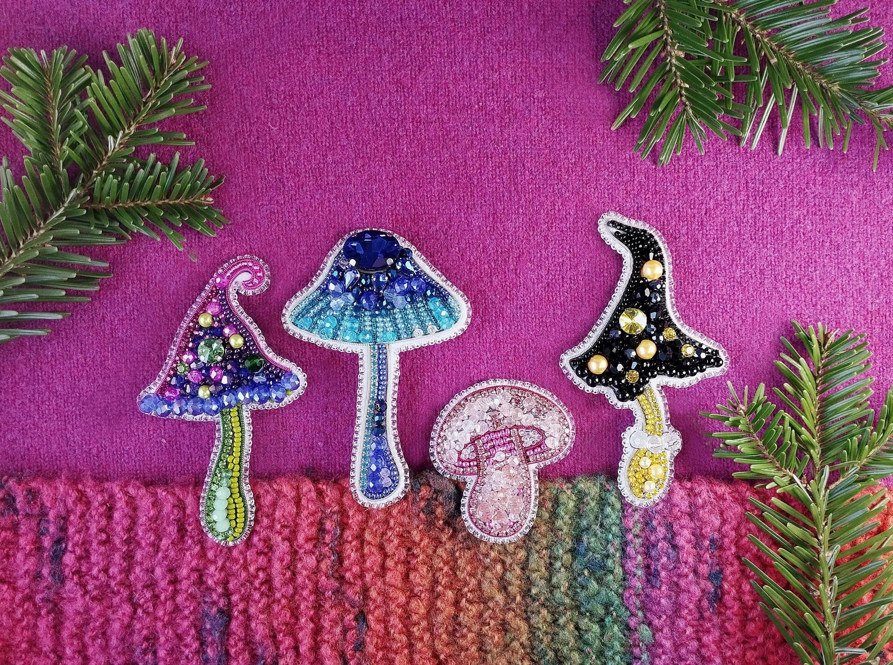 a group of three embroidered mushrooms sitting on top of a pink blanket