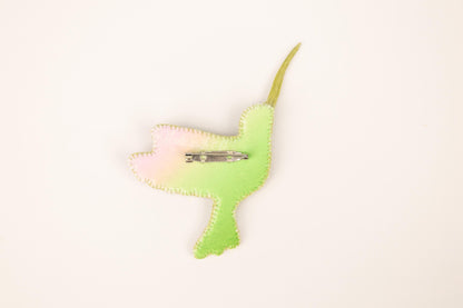 a green bird shaped brooch with a clip on it