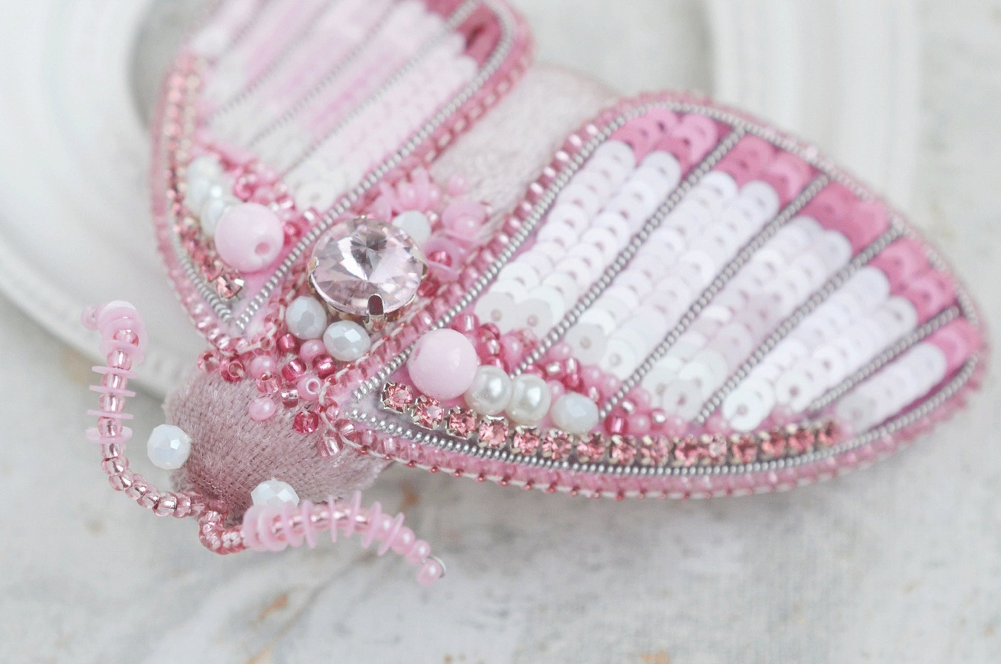 a close up of a pink and white butterfly brooch