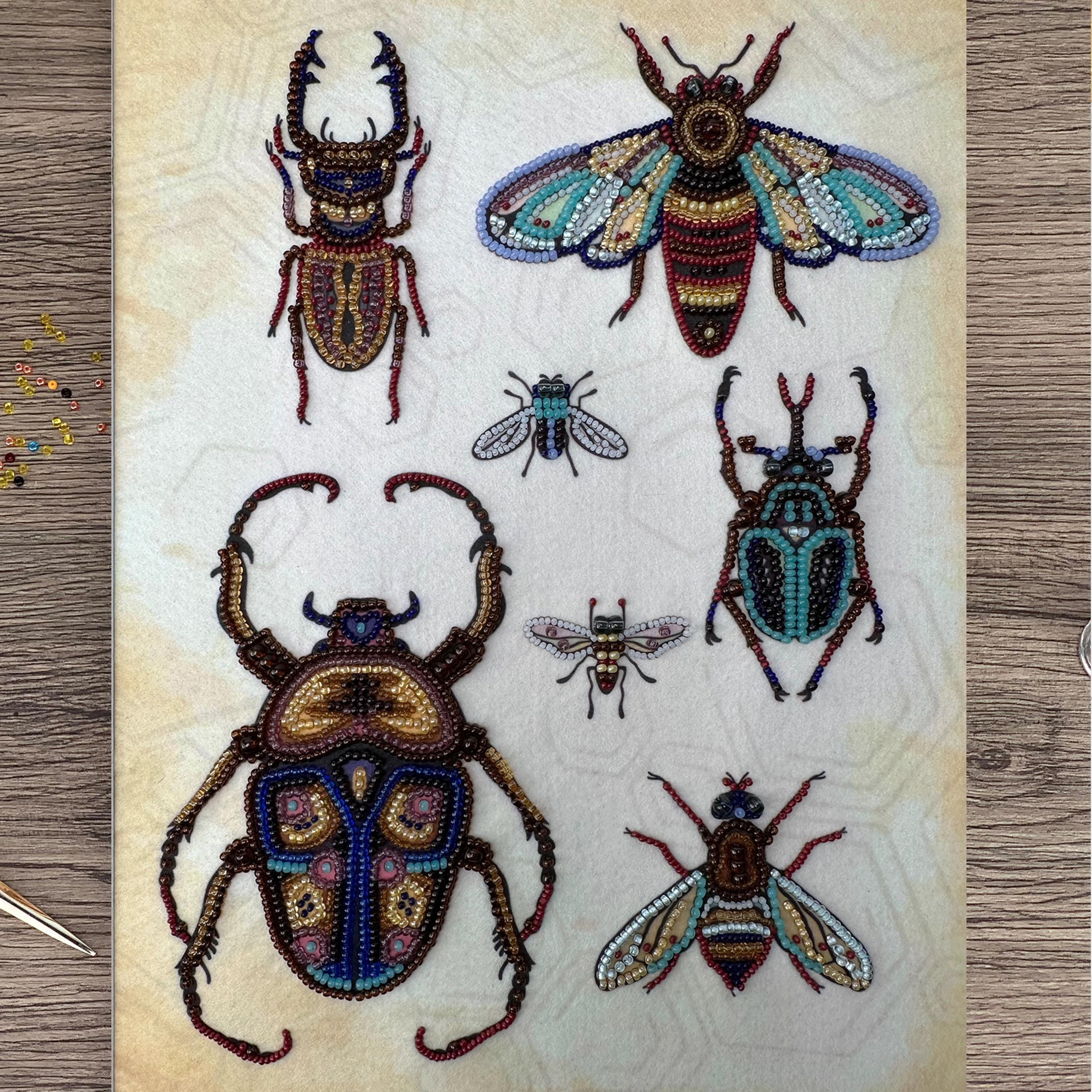 a collection of six intricately designed insects, including a large beetle, a colorful butterfly, and several smaller insects, all crafted from beads.