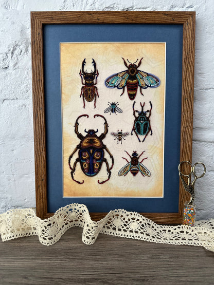 a framed collage of various colorful insects, including a large beetle, a bee, and several other insects, all set against a blue background.