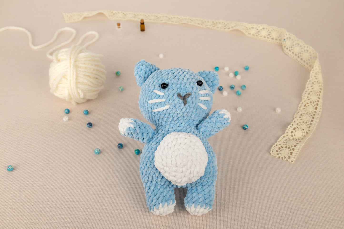 a crocheted kitty doll next to a ball of yarn