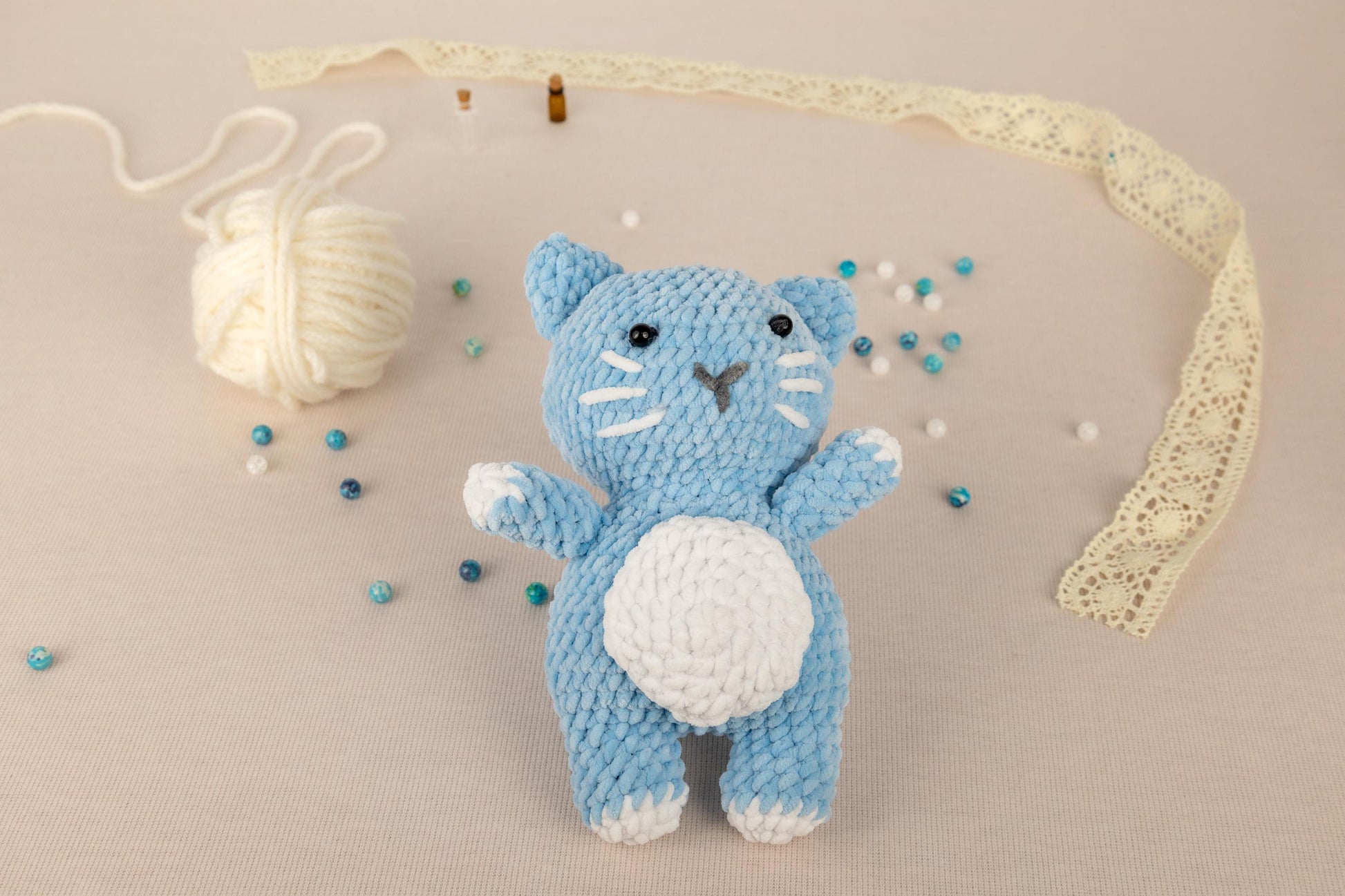 a crocheted kitty doll next to a ball of yarn