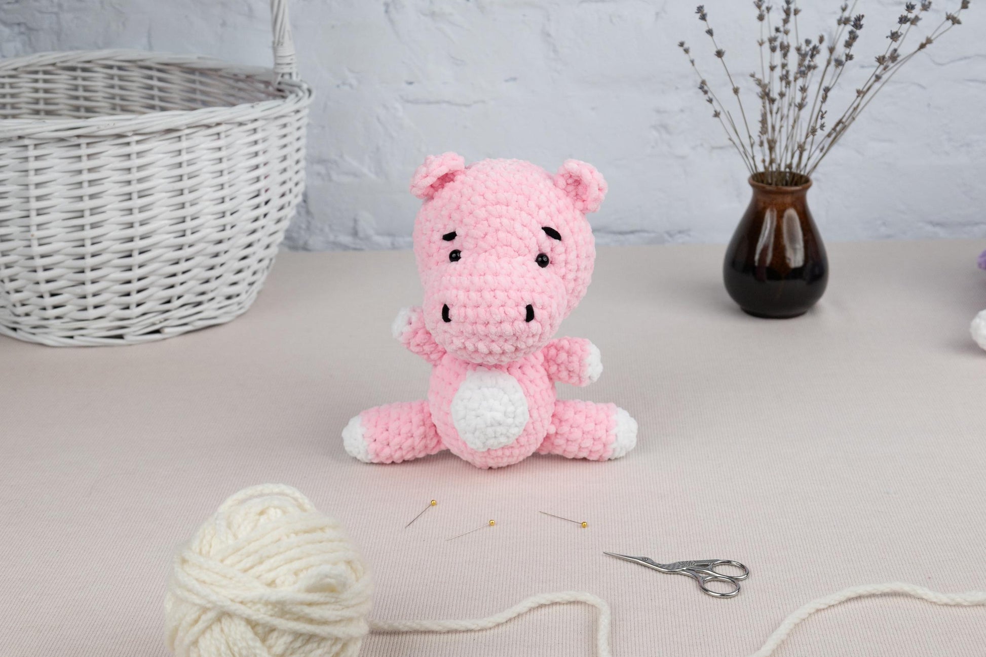 a crocheted pig sitting on a table next to a ball of yarn