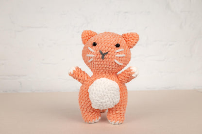a crocheted orange cat holding a white ball