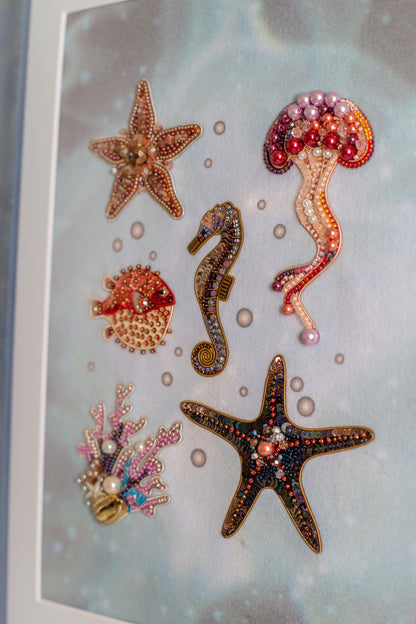 a collection of colorful, intricately designed sea-themed ornaments, including a starfish, a seahorse, a jellyfish, and a coral.