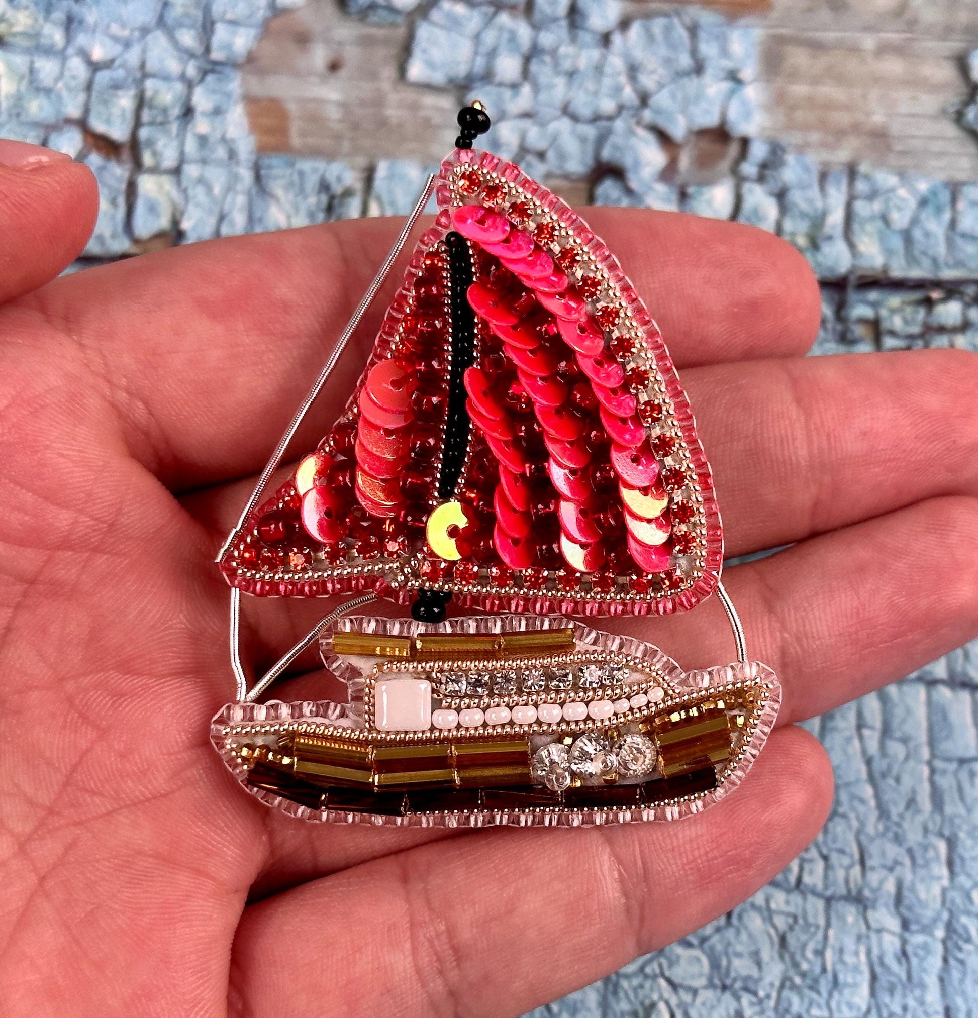 a hand holding a miniature model of a sailboat