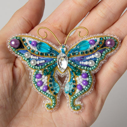 a hand is holding a beaded butterfly ornament