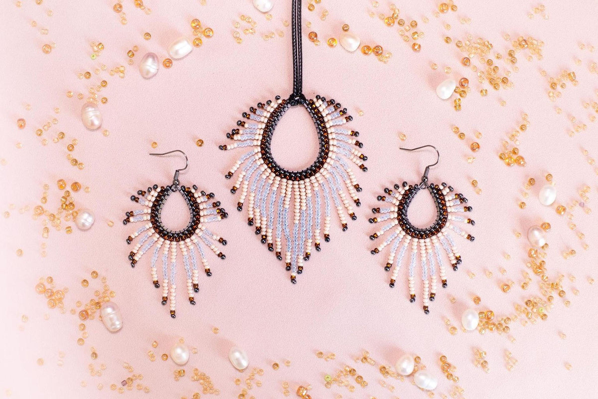 a necklace and earrings set with beaded designs, including a pendant and earrings, against a pink background with scattered pearls and beads.