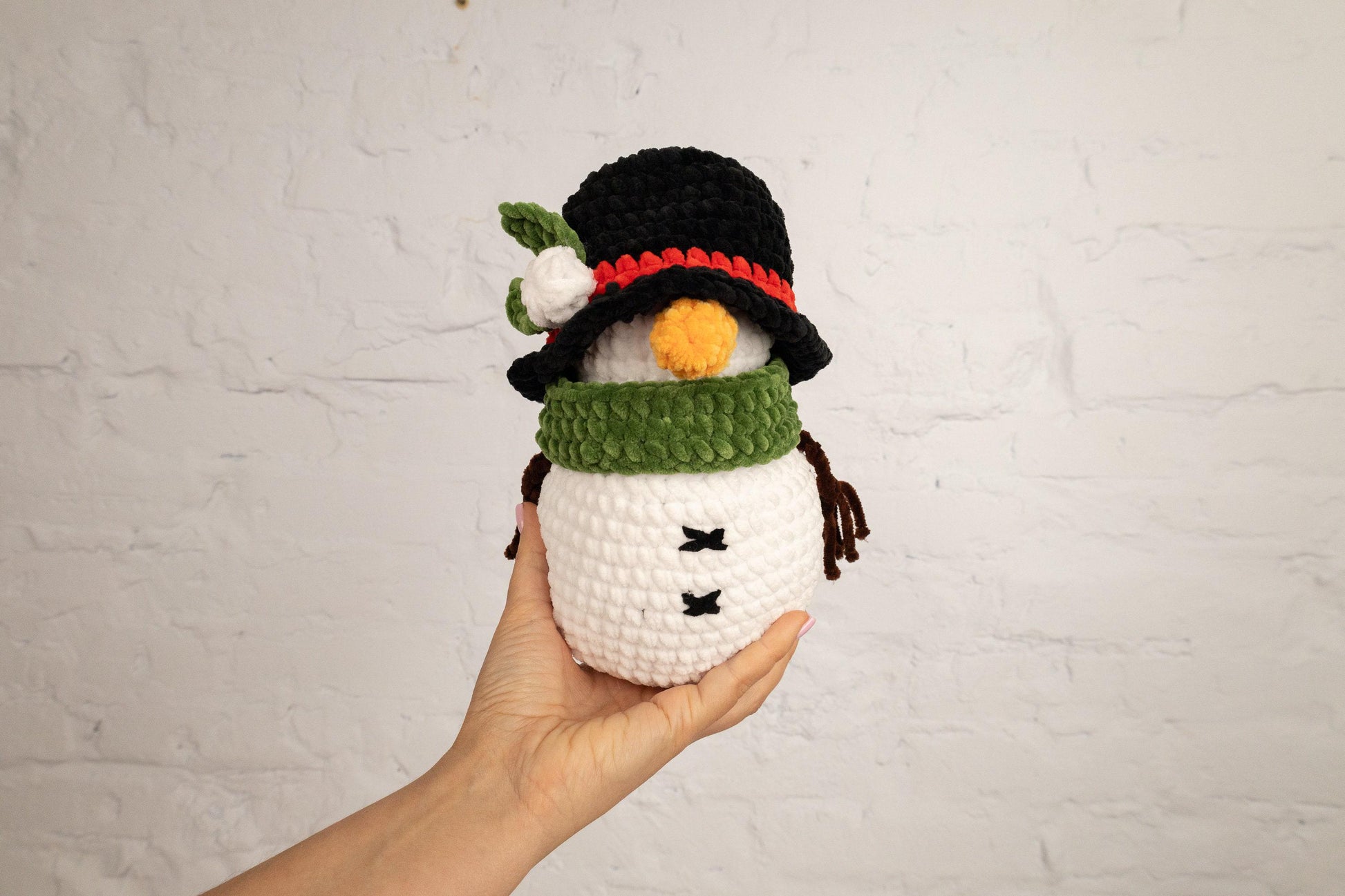 a hand holding a crocheted snowman ornament