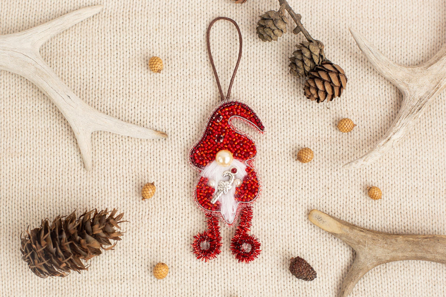 a Christmas ornament with red and white colors, surrounded by various natural elements such as pine cones, antlers, and acorns.