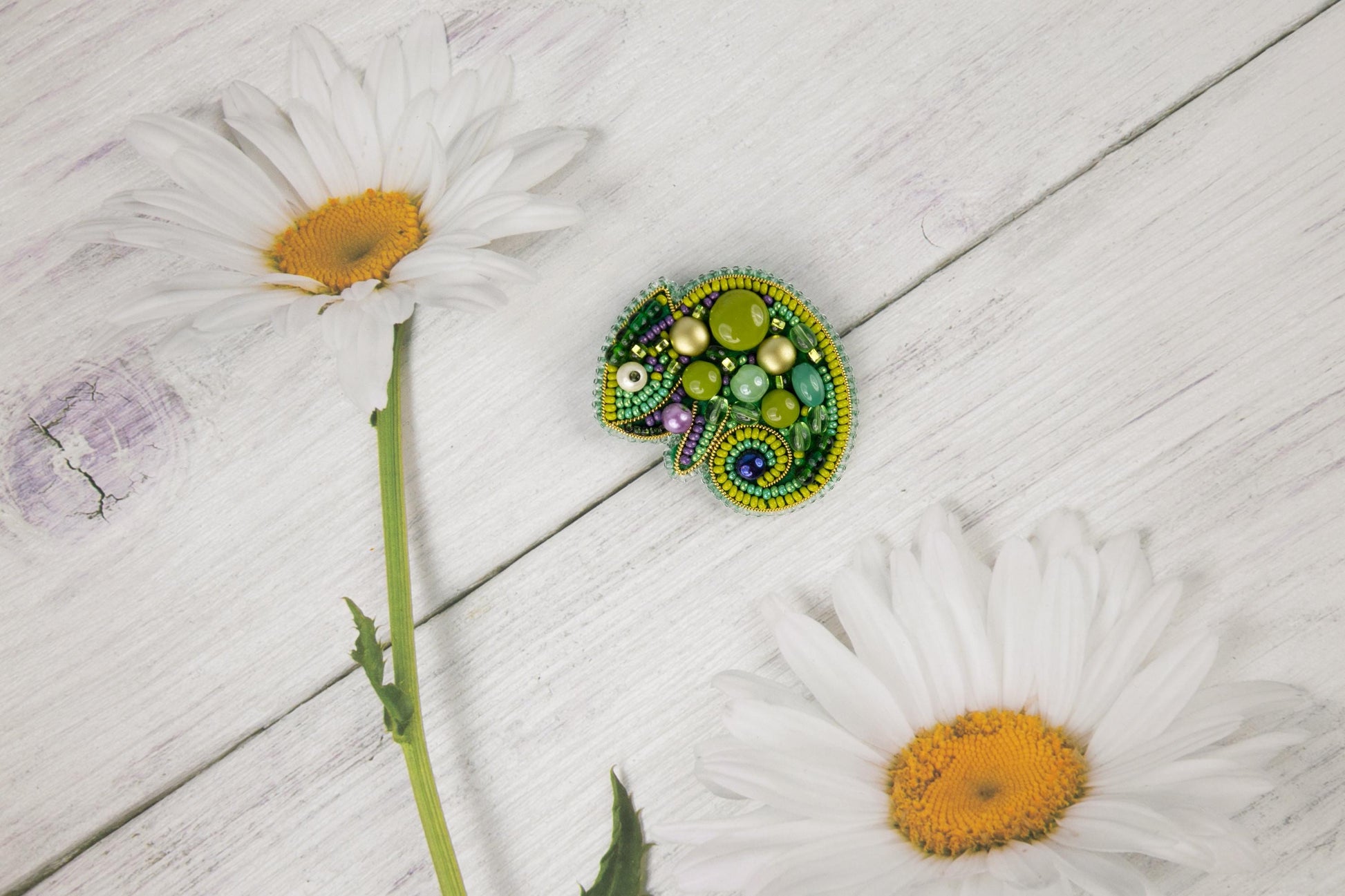 a green brooch sitting on top of a white flower