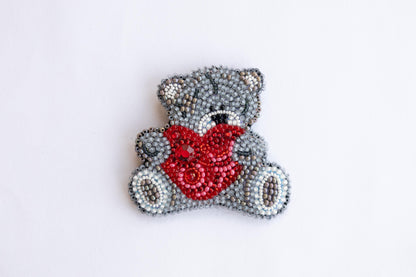 a beaded teddy bear with a red bow