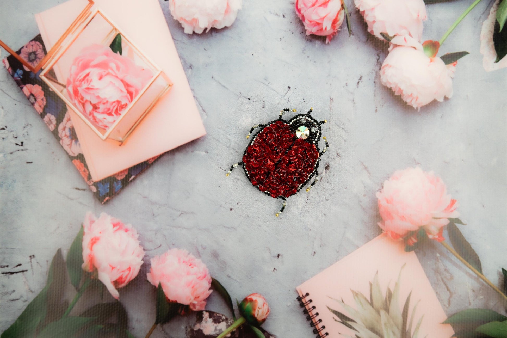 a heart shaped brooch sitting on top of a table next to flowers