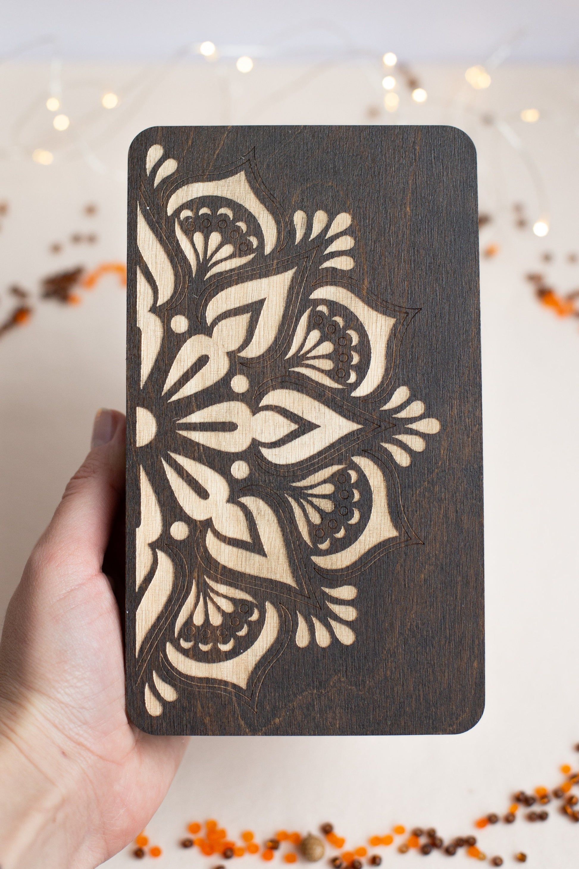 a hand holding a wooden card with a design on it