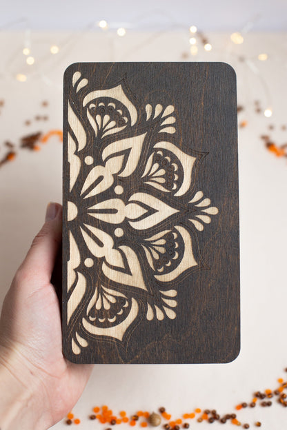 a hand holding a wooden card with a design on it