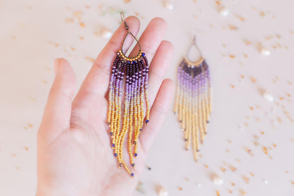 a hand holding a pair of beaded earrings