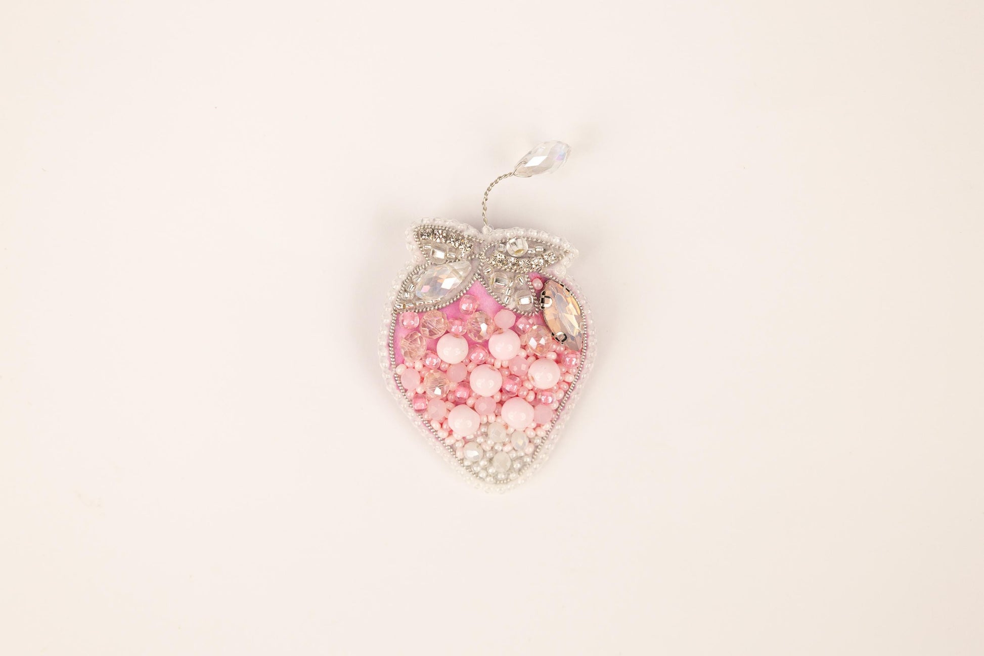 a pink and white heart shaped brooch on a white background