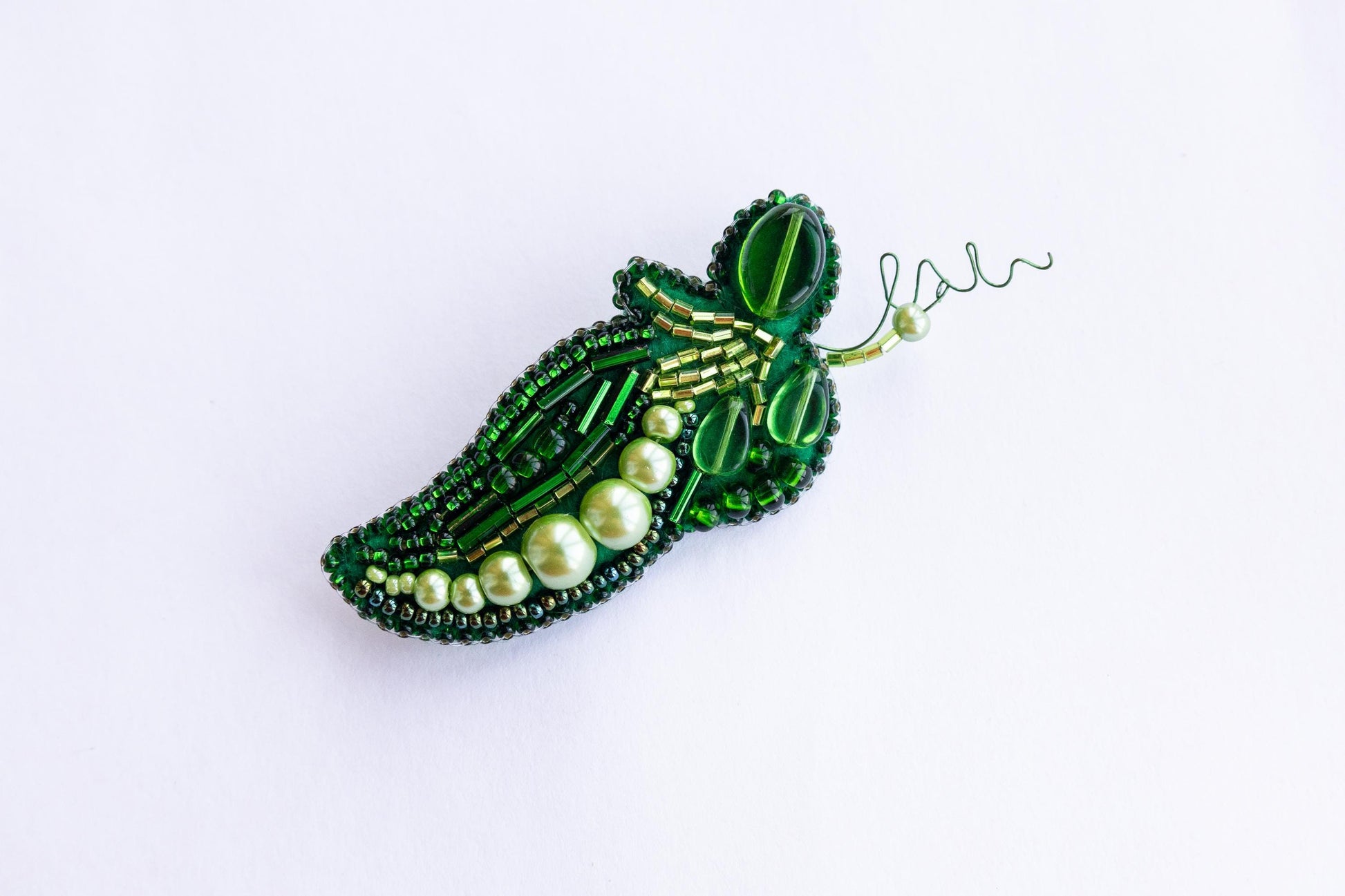 a green brooch with pearls and beads