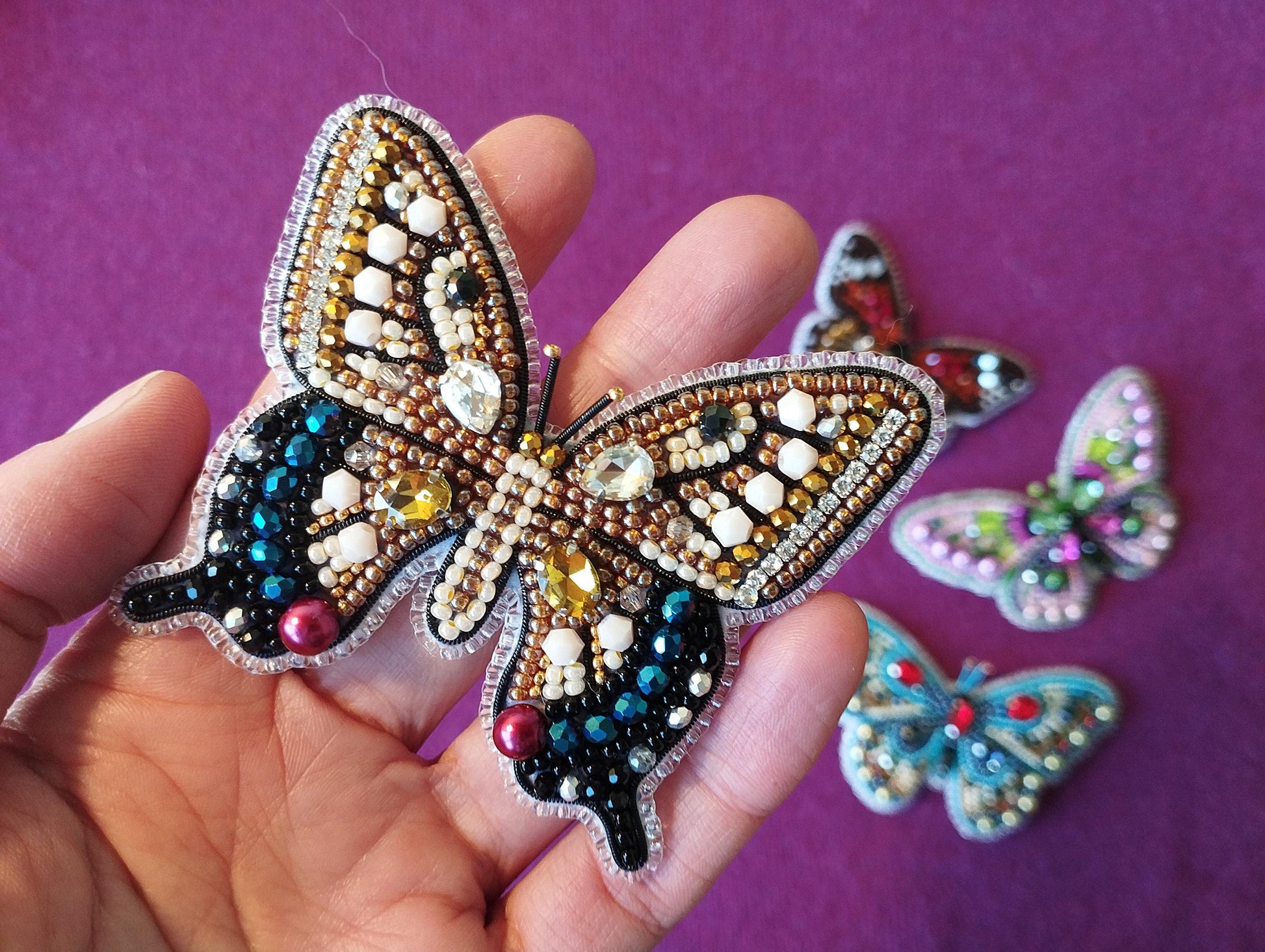 a person holding a butterfly brooch in their hand