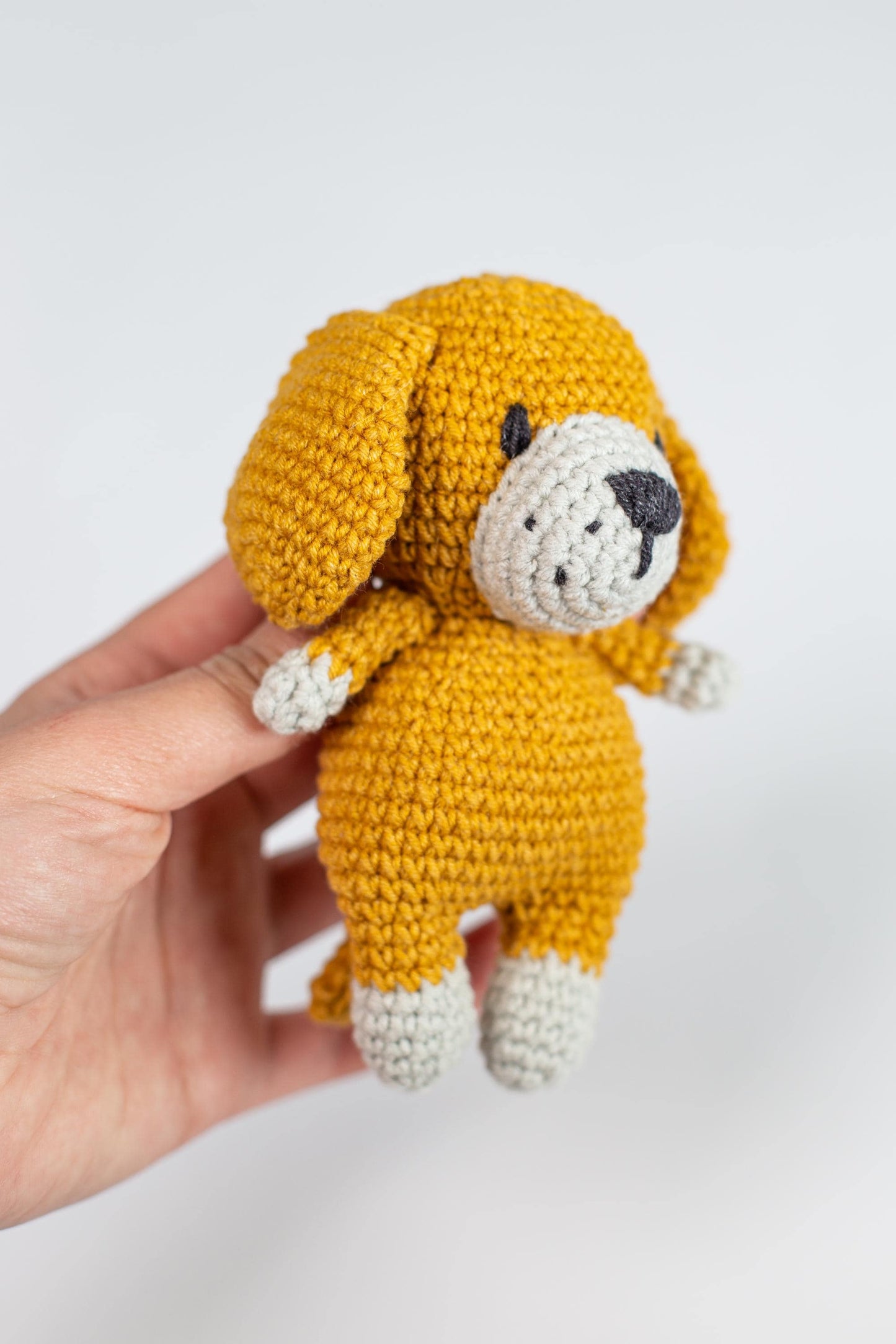 a hand holding a small yellow stuffed animal