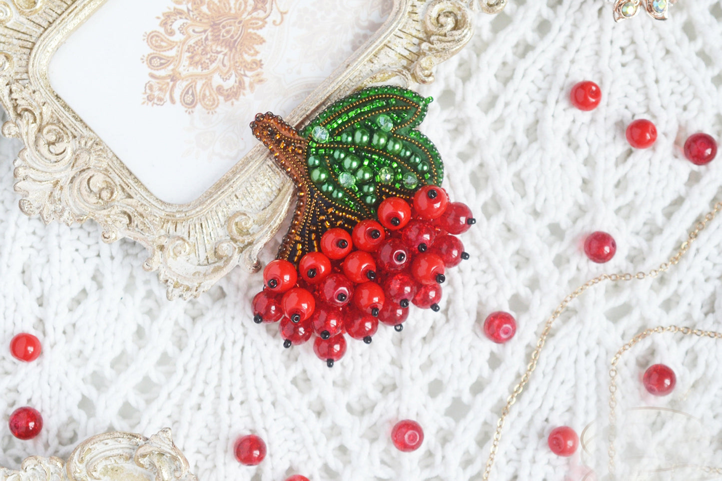 a close up of a red berry brooch on a white sweater
