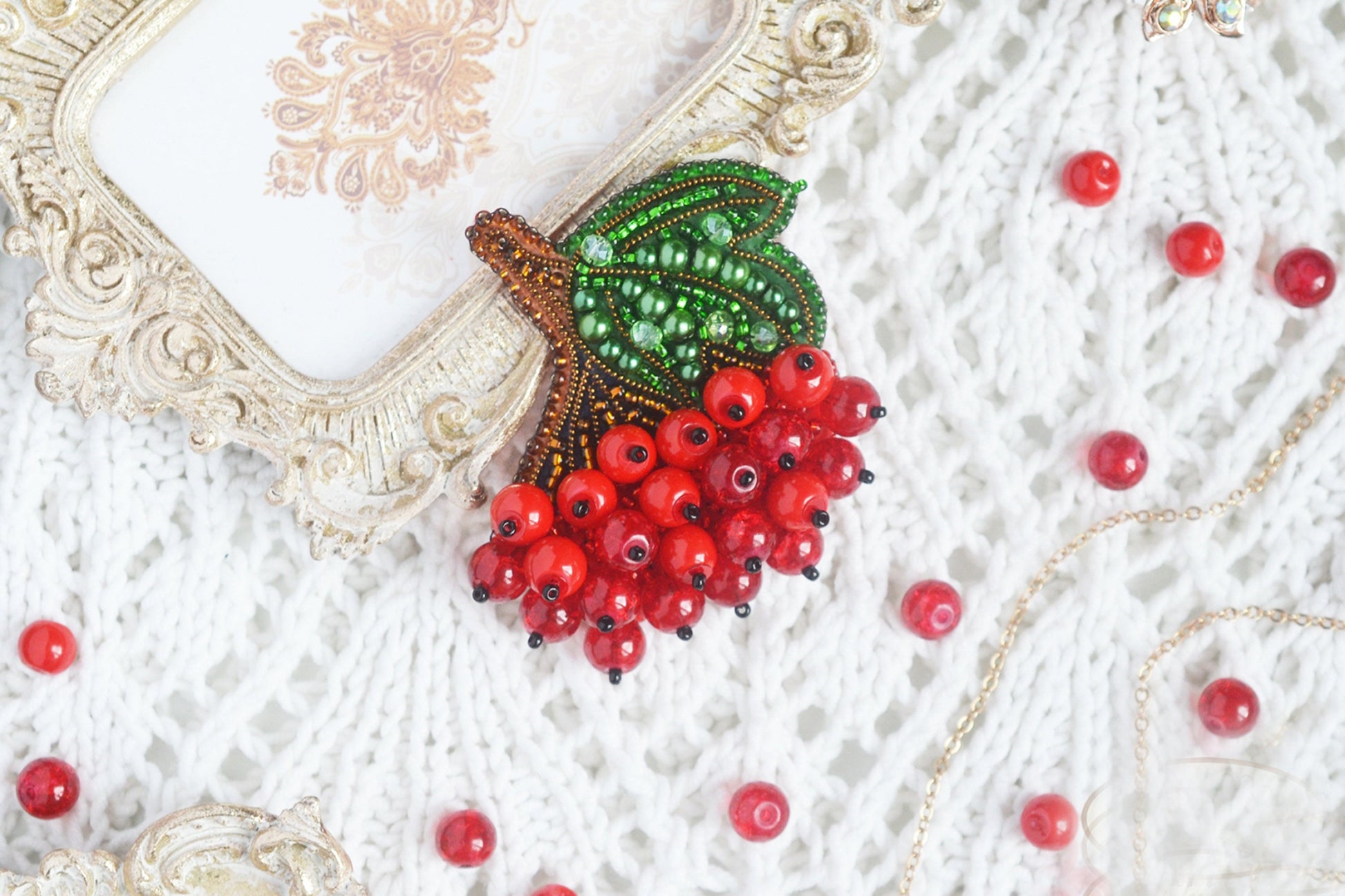 a close up of a red berry brooch on a white sweater