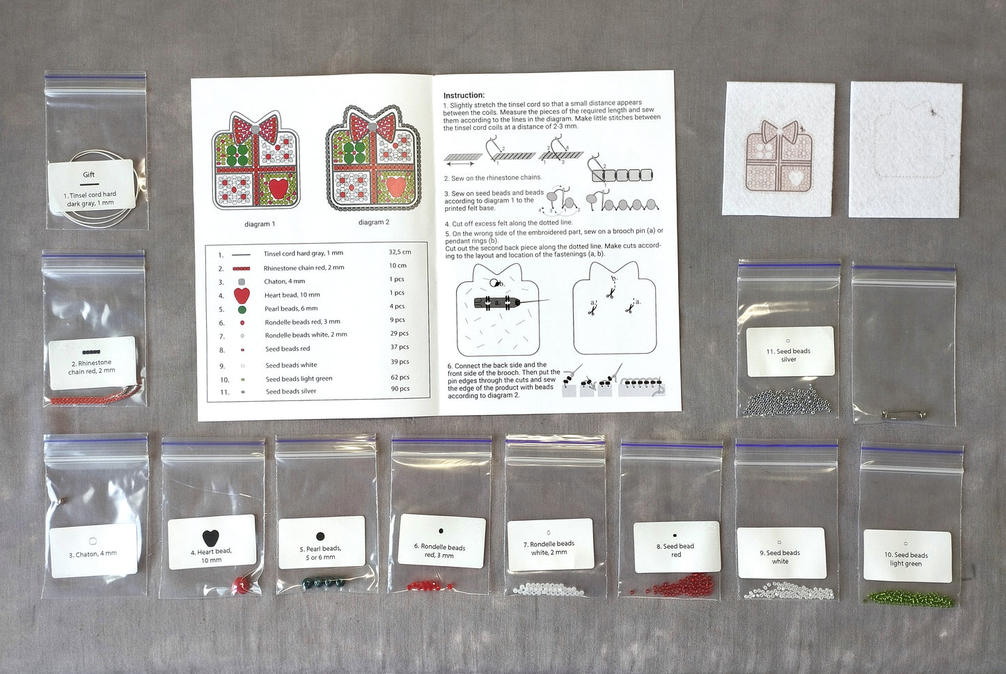 various craft supplies, including clear plastic bags, zippered bags, and instructions for a project. The supplies appear to be related to a sewing or embroidery project, with a focus on beads and other decorative elements.