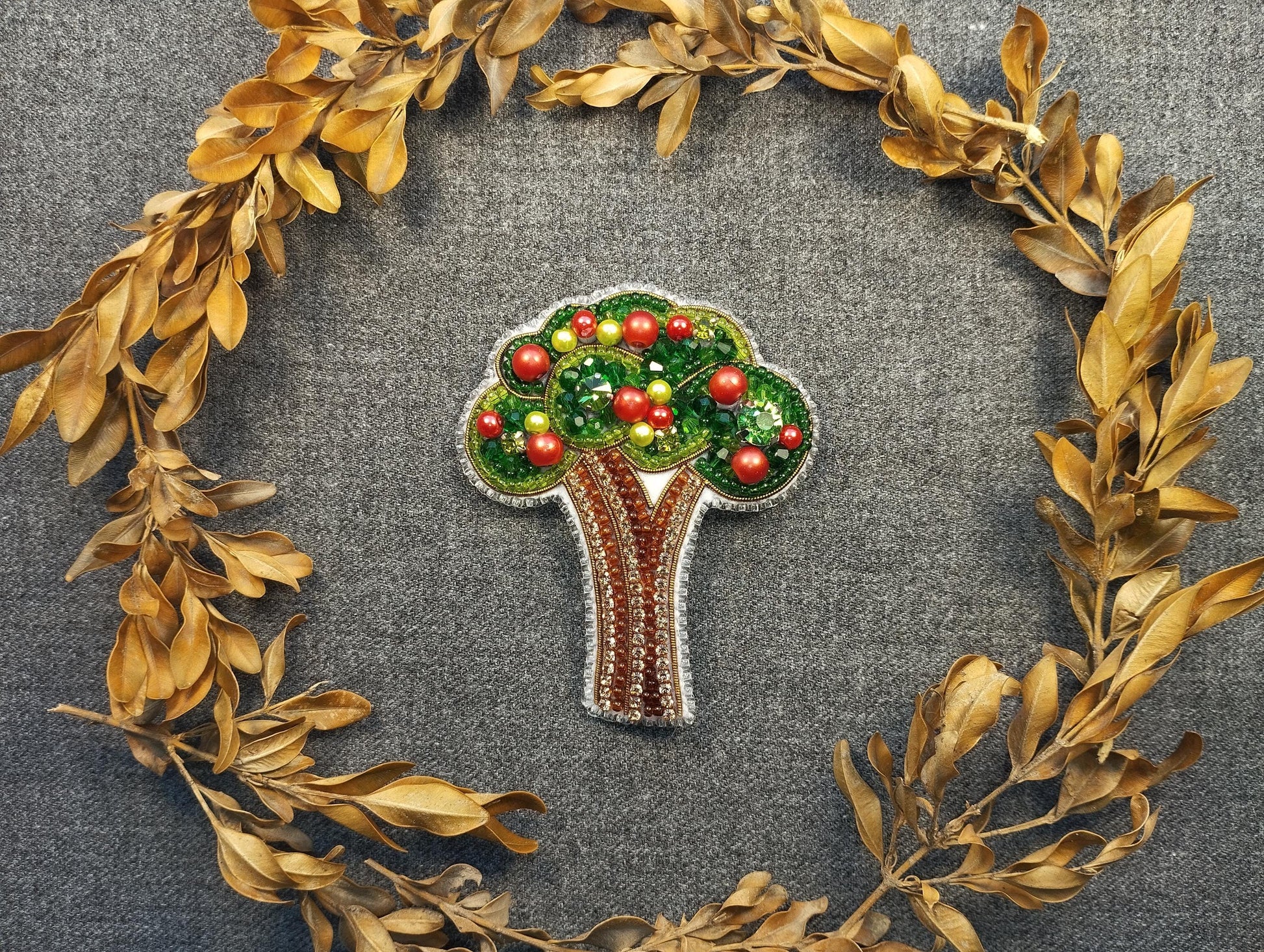 a brooch depicting a tree with apples on it