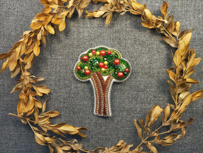 a brooch depicting a tree with apples on it