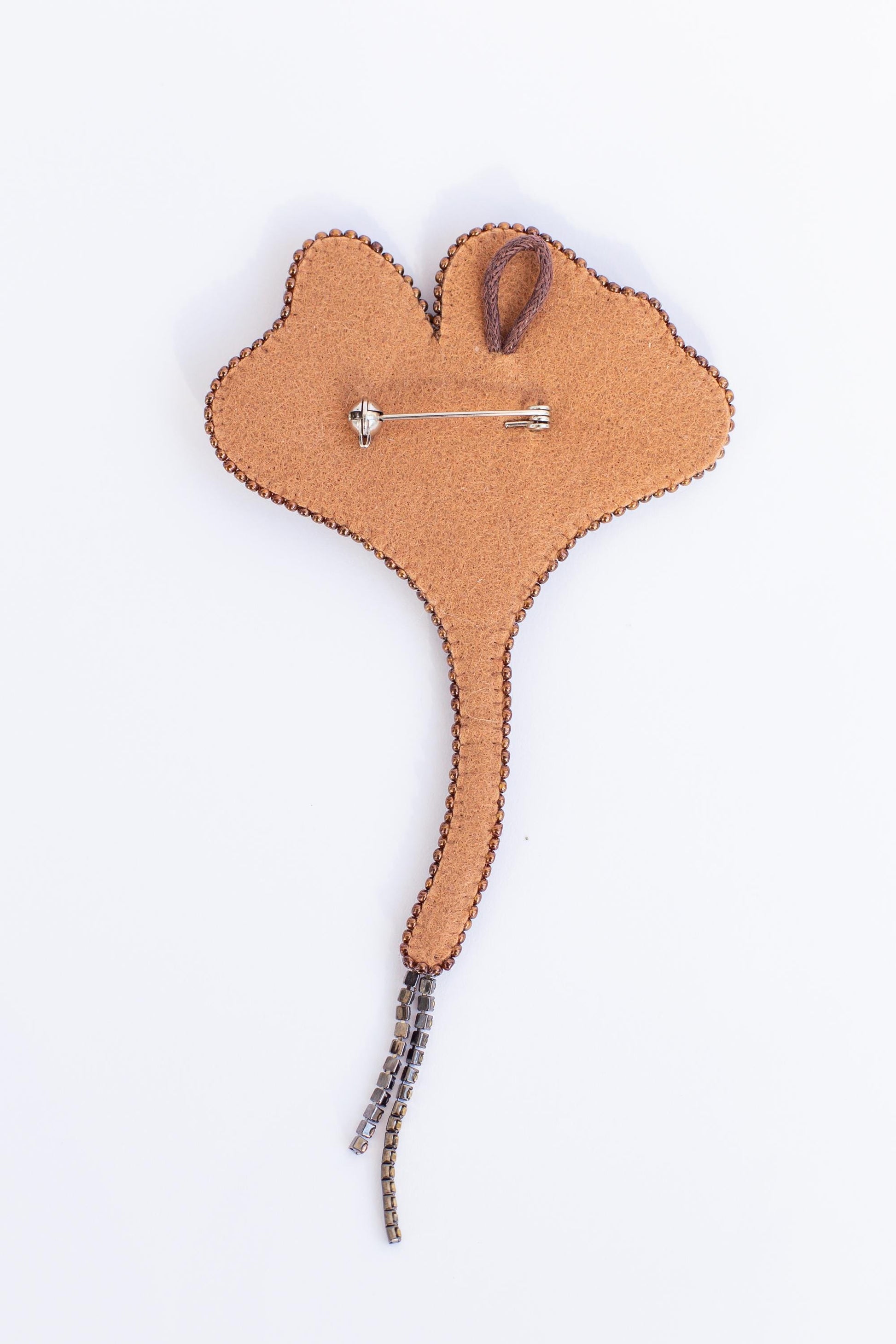 a brown felt pin with a silver pin attached to it, set against a white background.