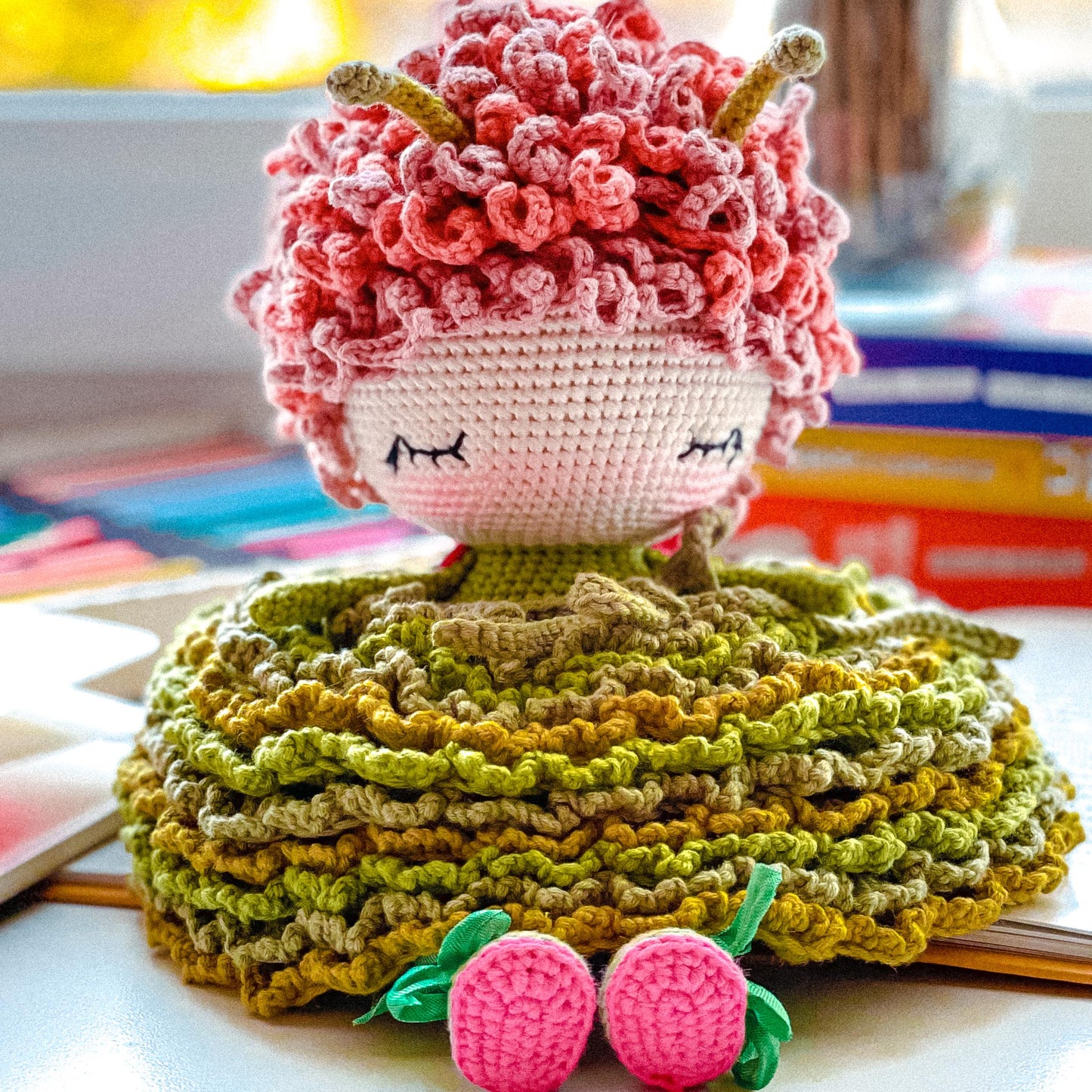 a crocheted doll sitting on top of a pile of books