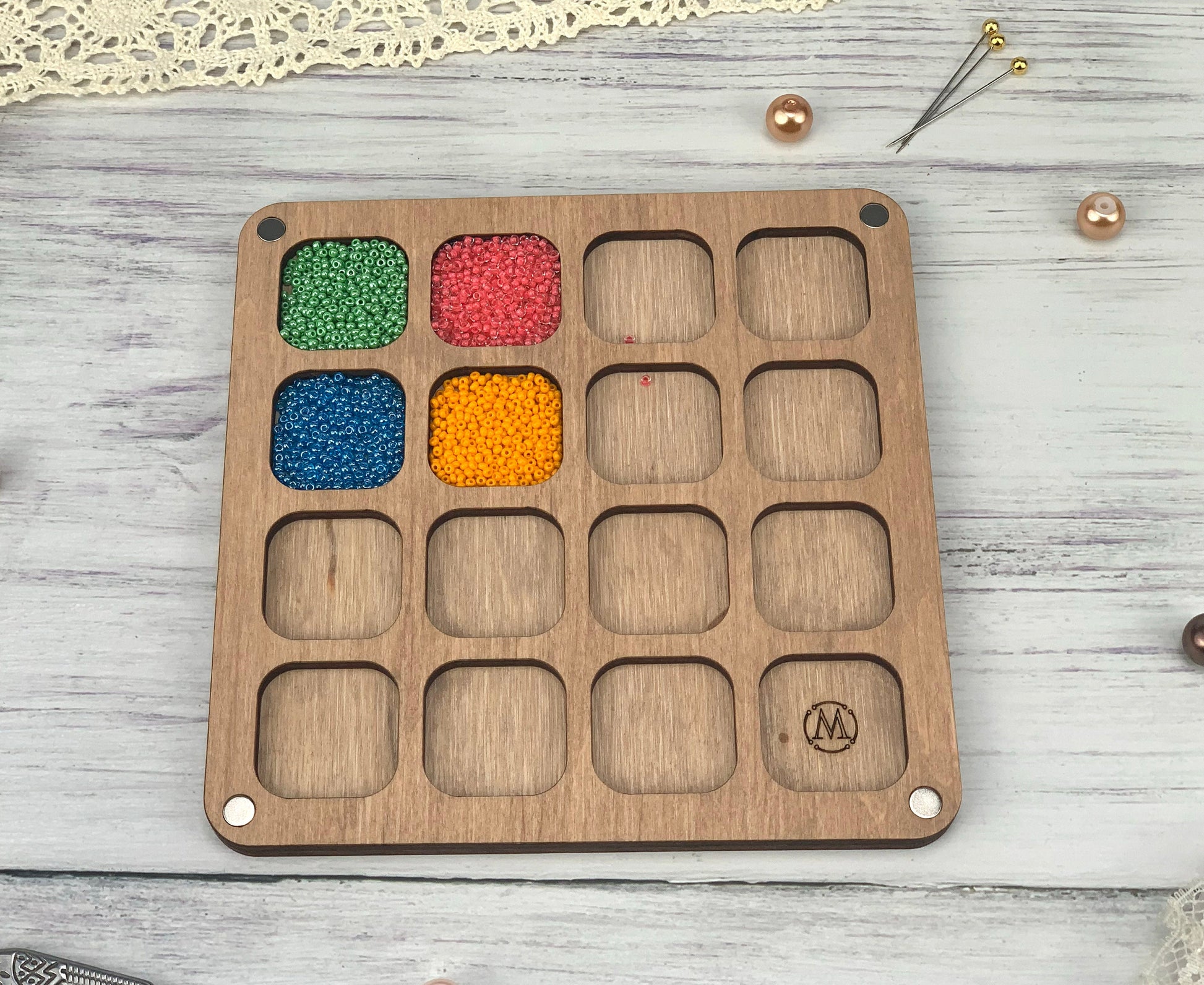 a wooden tray with beads in it on a table