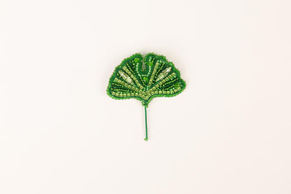 a green beaded leaf on a white background