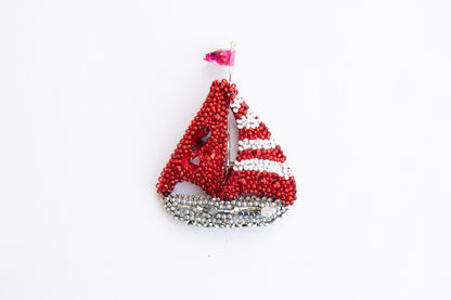 a red and white beaded sailboat ornament