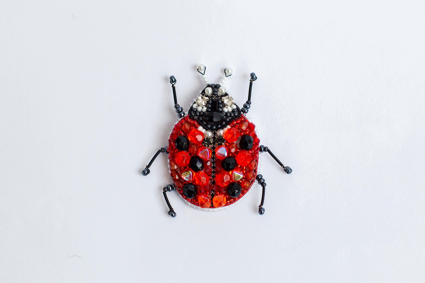 a ladybug made out of beads on a white surface
