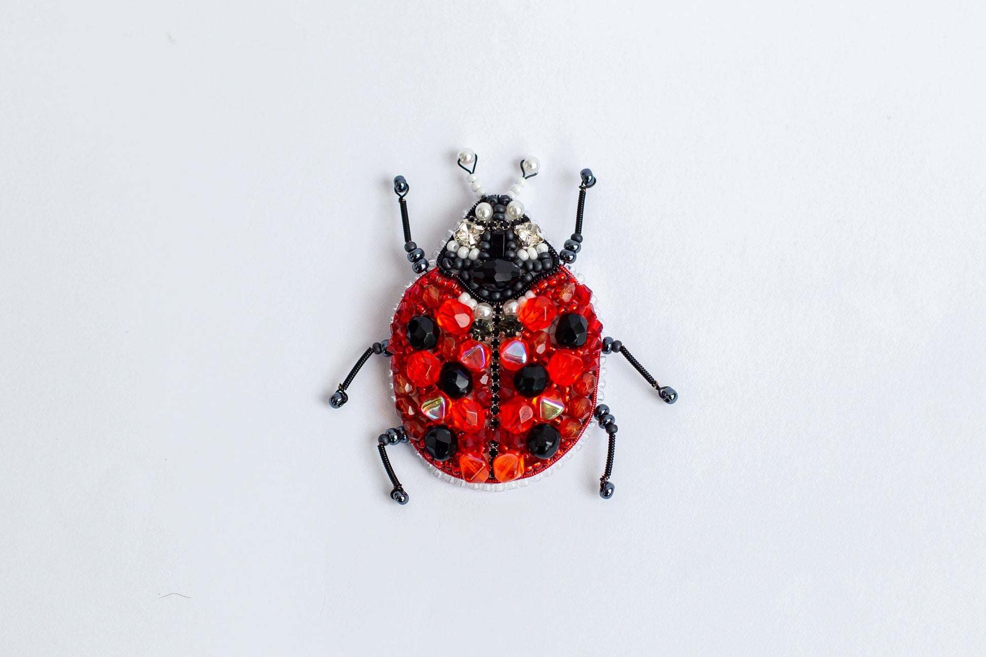 a ladybug made out of beads on a white surface