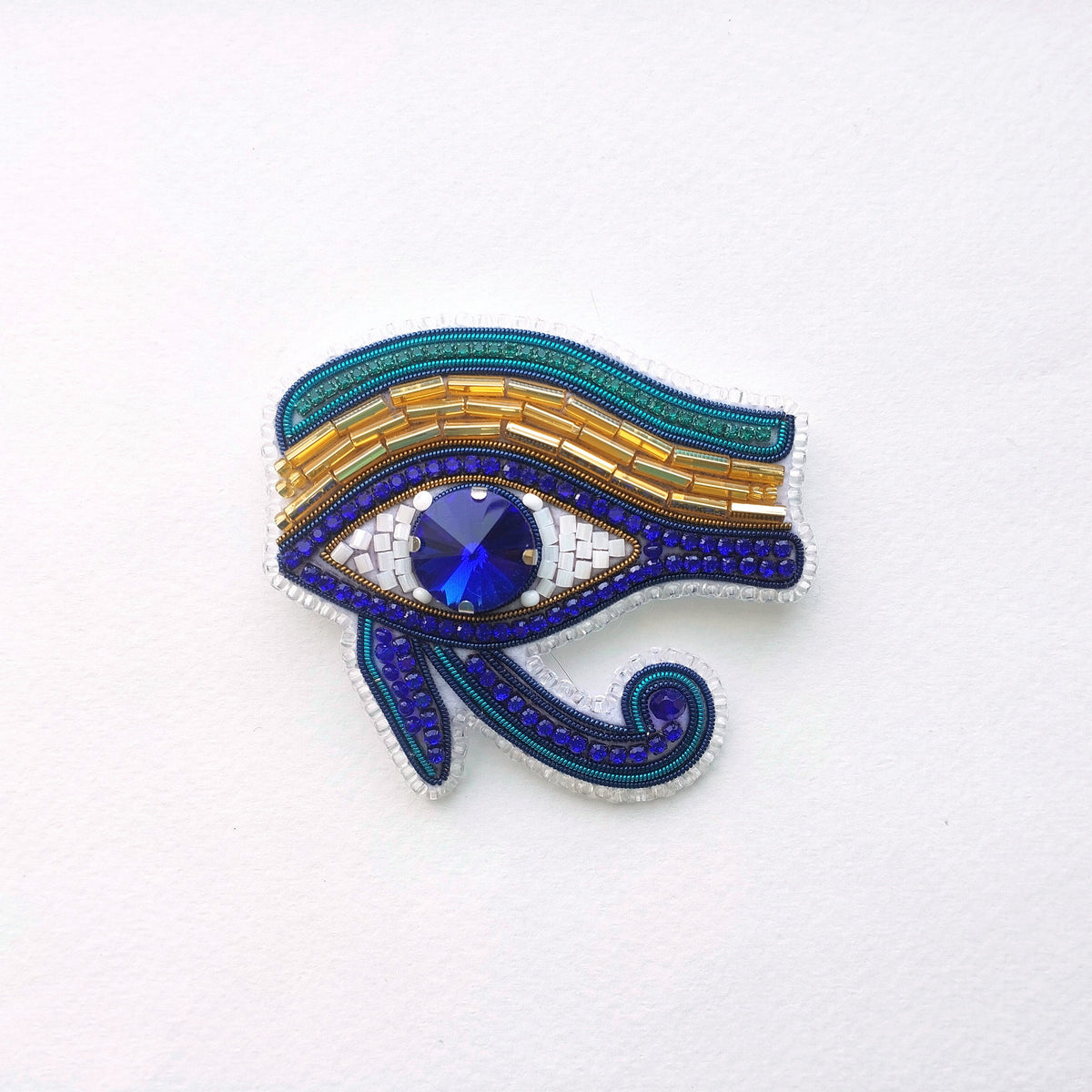 a decorative piece of jewelry, specifically a brooch or pin, with a large blue gemstone in the center. The piece is adorned with intricate patterns and designs, showcasing the craftsmanship and artistry involved in its creation.