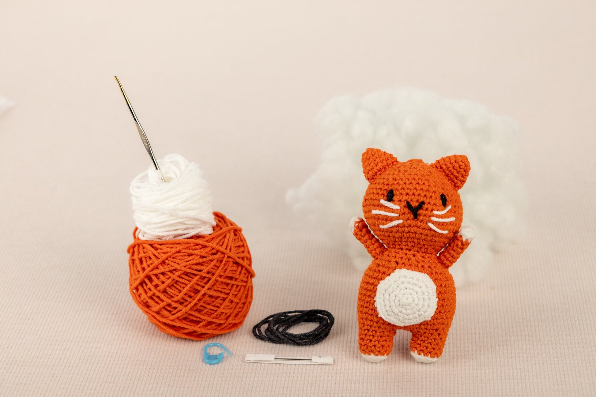 a crocheted cat next to a ball of yarn