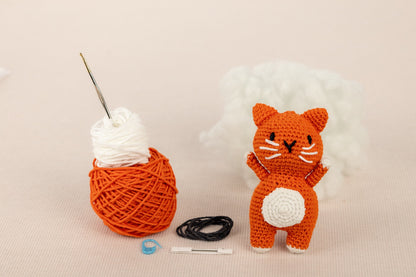 a crocheted cat next to a ball of yarn