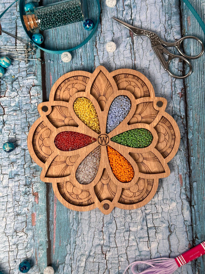 a wooden cutout of a flower surrounded by beads and a pair of scissors