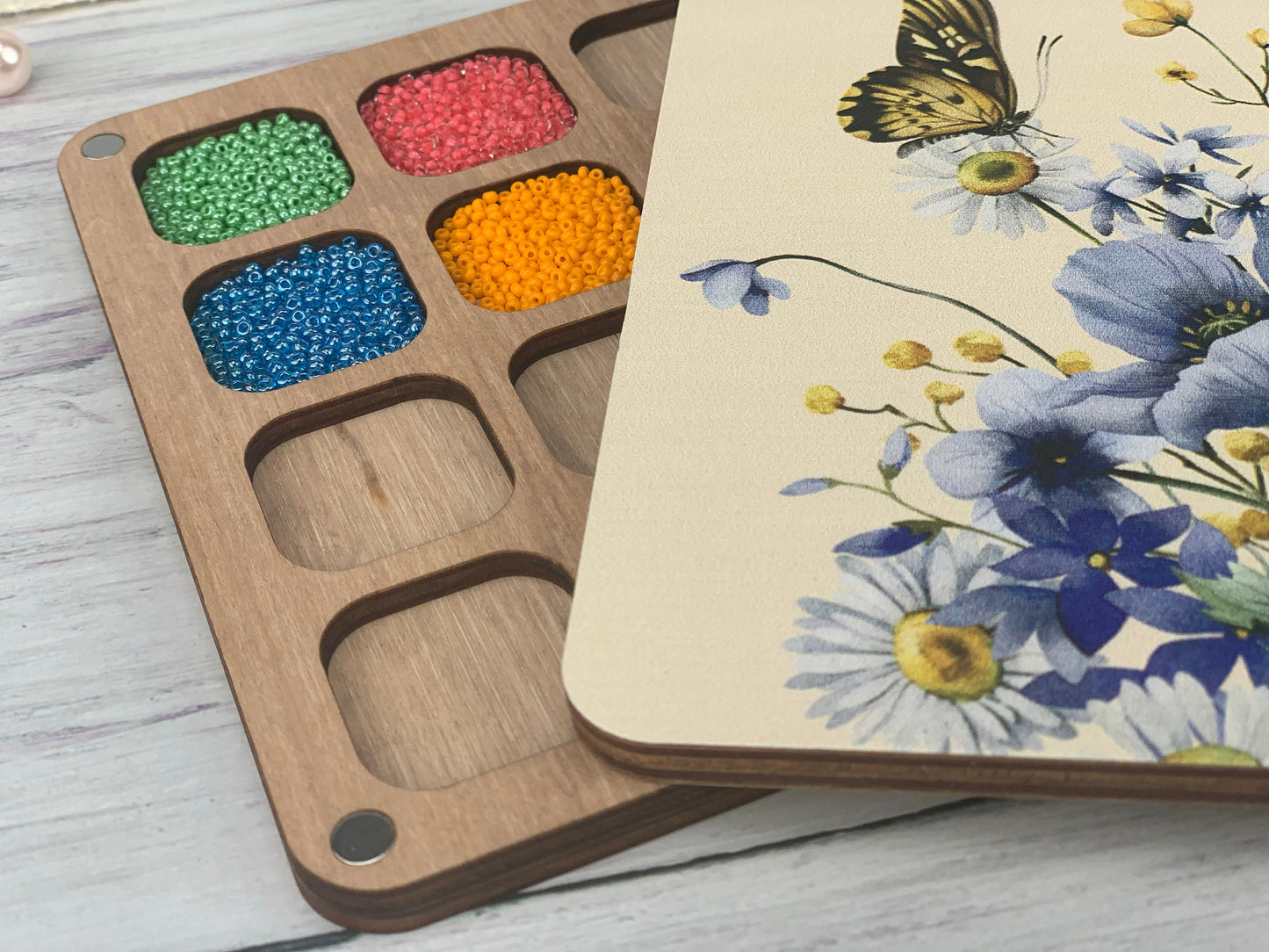 a box of beads next to a wooden box with a butterfly on it