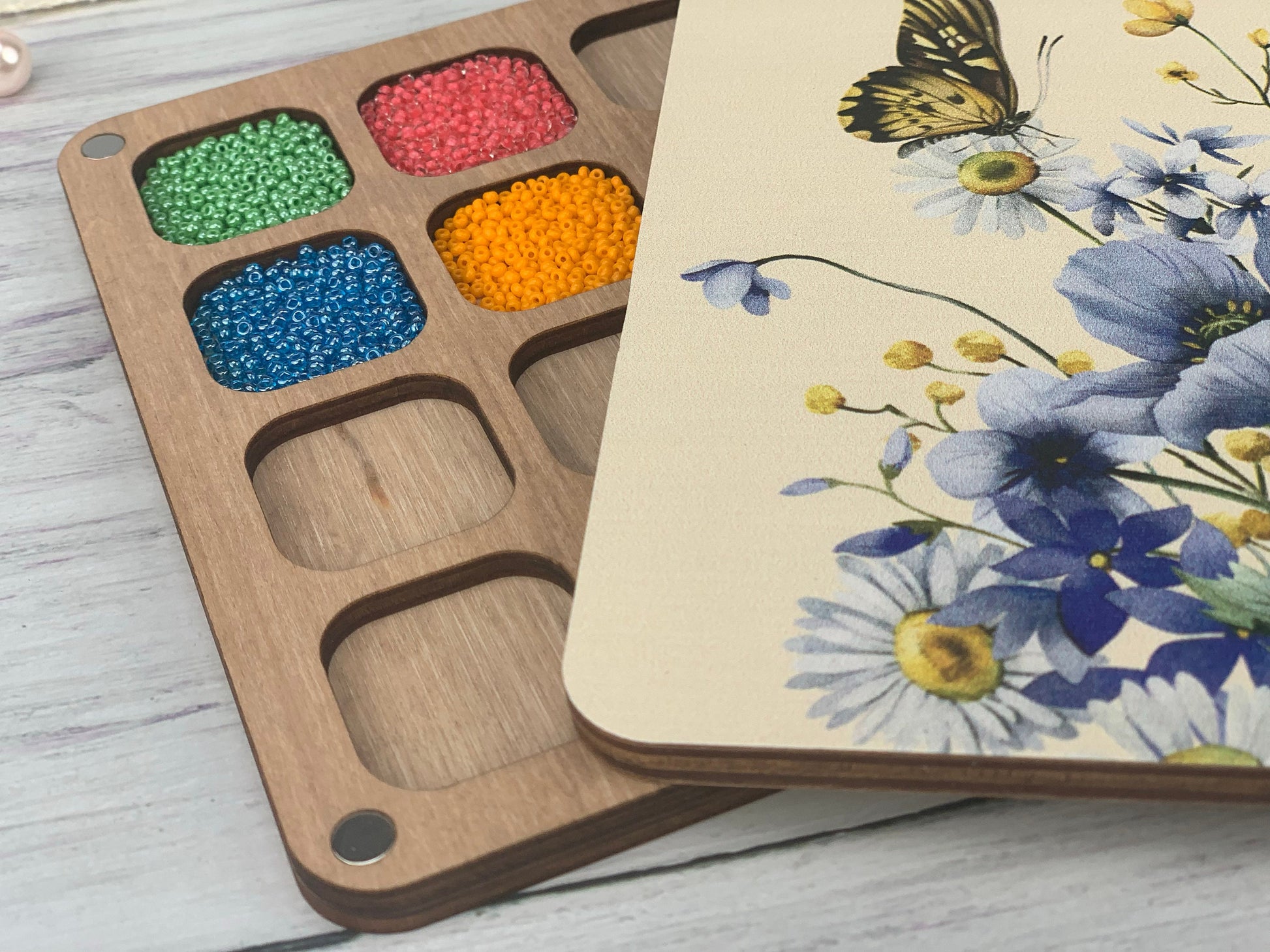 a box of beads next to a wooden box with a butterfly on it