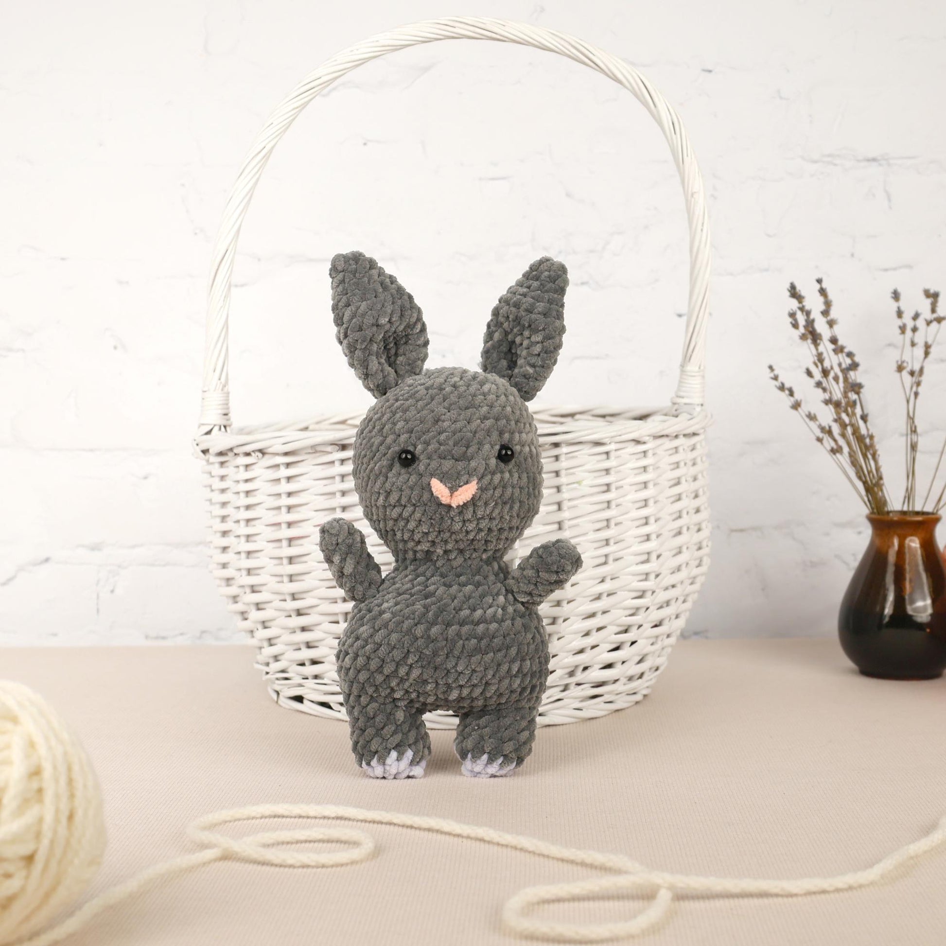 a knitted bunny sitting next to a basket of yarn