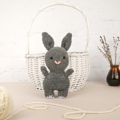 a knitted bunny sitting next to a basket of yarn
