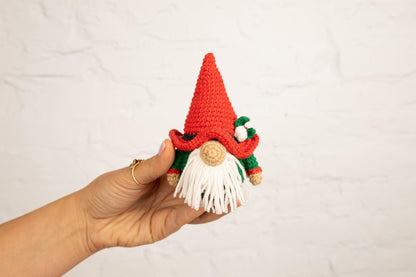 a hand holding a small crocheted gnome&#39;s hat