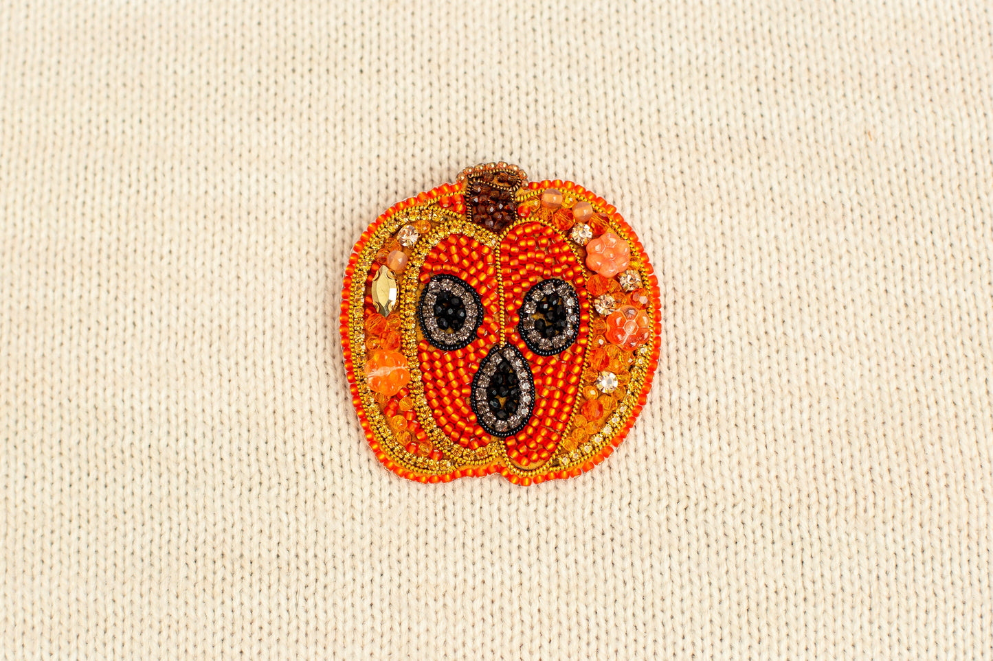 a close up of a beaded pumpkin on a white surface