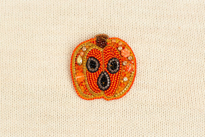 a close up of a beaded pumpkin on a white surface