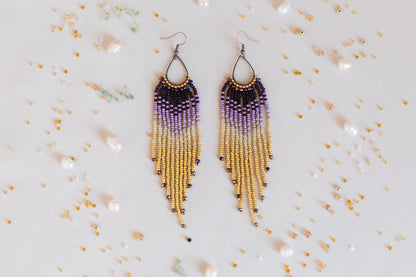 a pair of purple and yellow beaded earrings